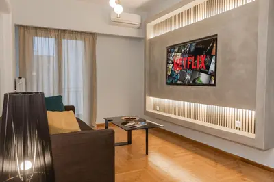 a living room with a couch and a tv on a wall at Acropolis experience apartment! in Athens