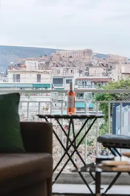 a table with a bottle of wine on a balcony at Acropolis experience apartment! in Athens