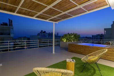 a balcony with two chairs and a tub on a roof at Jacuzzi Penthouse with sea view 5th floor in Athens