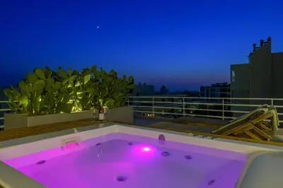 a hot tub on top of a balcony at night at Jacuzzi Penthouse with sea view 5th floor in Athens