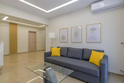 a living room with a blue couch and yellow pillows at Brand new 3bedrooms apartment in Athens