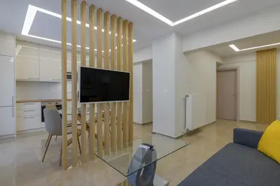 a living room with a tv and a table with a chair at Brand new 3bedrooms apartment in Athens