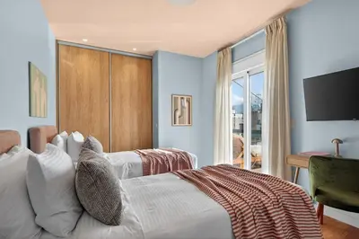 a bedroom with a white bed with a television on the wall at Fireside Kallithea - Large Veranda II - 3BR by ΜΡS in Athens
