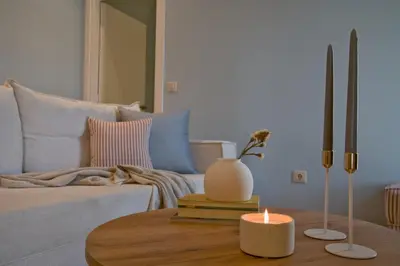a living room with a couch and a candle on a table at Fireside Kallithea - Large Veranda I -2BR by ΜΡS in Athens