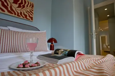 a plate of fruit and a glass of wine on a bed at Fireside Kallithea - Large Veranda I -2BR by ΜΡS in Athens