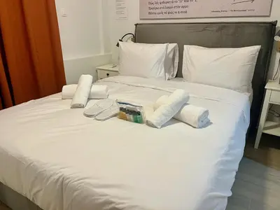 a white bed with two pillows and towels on it at Carlo's Apartment in Athens