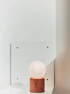 a white lamp on a wooden stand in a room at An Interior in Its Purest Form in Athens