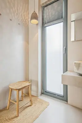 a wooden stool in a room with a window at Living Beyond Design in Athens