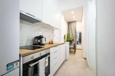 a kitchen with white cabinets and a stove top oven at Modern Studio l King Bed & Work Corner in Athens