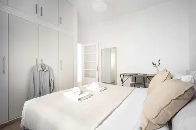 a white bedroom with a bed and a mirror at Bright Cozy 2BR l Private Balcony & Work Corner in Athens