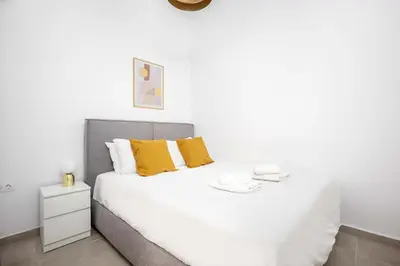 a white bedroom with a large bed with yellow pillows at Bright Cozy 2BR l Private Balcony & Work Corner in Athens