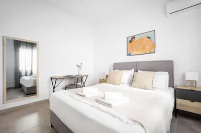 a white bedroom with a large bed and a mirror at Bright Cozy 2BR l Private Balcony & Work Corner in Athens