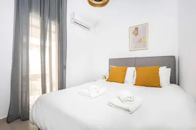 a bedroom with a large white bed with yellow pillows at Bright Cozy 2BR l Private Balcony & Work Corner in Athens