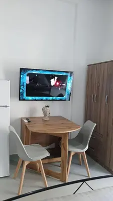 a wooden table with two chairs and a tv on a wall at Афіни Лофт in Piraeus
