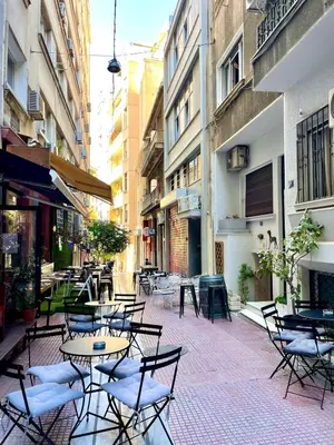 an outdoor patio with tables and chairs and buildings at Athenian blue in Athens