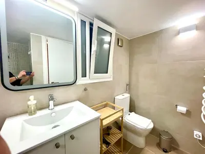 a person taking a picture of a bathroom with a sink and toilet at Athenian blue in Athens