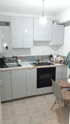 a kitchen with white cabinets and a black oven at Kipsely room in Athens