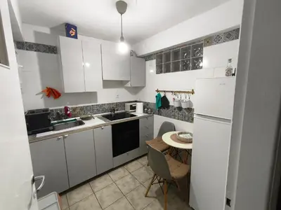 a small kitchen with white cabinets and a table at Kipsely room in Athens