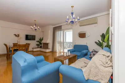 a living room with blue chairs and a table at Raise Glyfada Sky Residence in Athens