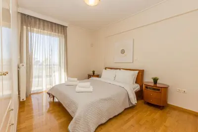 a white bedroom with a large bed and a window at Raise Glyfada Sky Residence in Athens