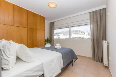 a bedroom with a bed and a large window at Raise Glyfada Sky Residence in Athens