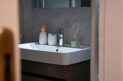 a white bathroom sink with soap and a mirror at Stylish Modern apartment, 10' from the center! in Athens