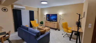 a living room with a blue couch and yellow chairs at Dramas17 - PS5 in Piraeus