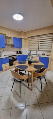 a kitchen with blue cabinets and a table and chairs at Dramas17 - PS5 in Piraeus