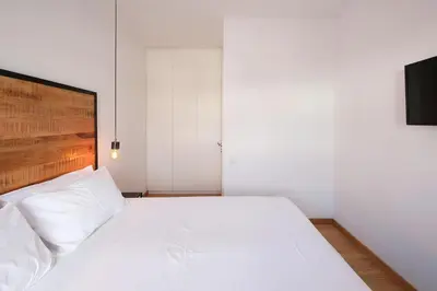a bedroom with a white bed with a wooden headboard at Glyfada Amazing Suite with sea view & jacuzzi in Athens