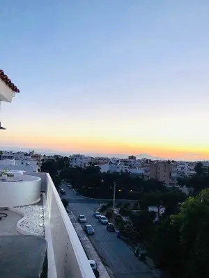 a view of a city at sunset from a balcony at Glyfada Amazing Suite with sea view & jacuzzi in Athens