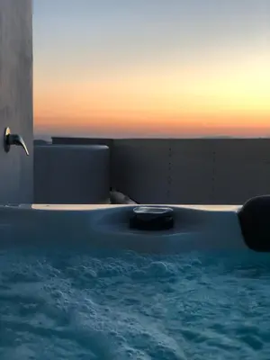 a large blue bath tub with a sunset in the background at Glyfada Amazing Suite with sea view & jacuzzi in Athens