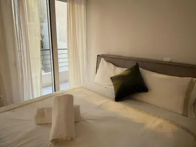 a white bed with a black pillow and a window at Estía Cozy City Apartment in Athens