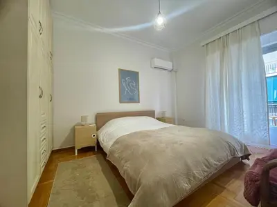 a white bedroom with a bed and a window at Tranquil Athenian Home - City Center in Athens