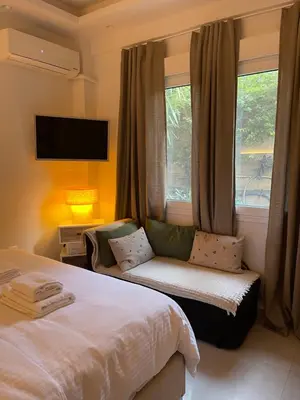 a bedroom with a bed and a window with a couch at Athenee Riviera in Athens