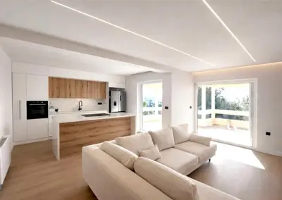 a living room with a white couch and a kitchen at Voula Seaview Residence in Athens