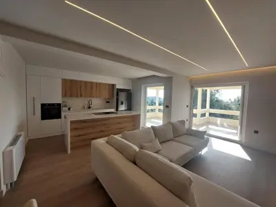 a living room with a white couch and a kitchen at Voula Seaview Residence in Athens