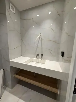 a white bathroom with a sink and marble walls at Voula Seaview Residence in Athens