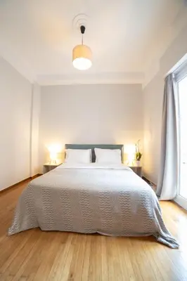 a white bedroom with a bed and a window at Athens Imperial Suite 1 in Athens