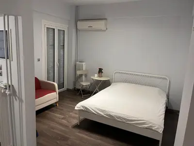 a bedroom with a white bed and a red chair at Studio by Acropolis in Athens