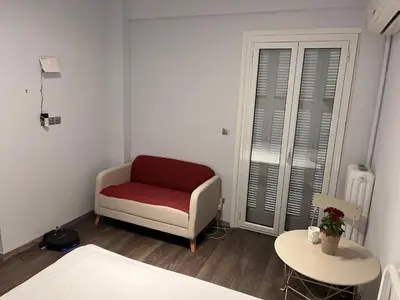 a bedroom with a red chair and a table at Studio by Acropolis in Athens