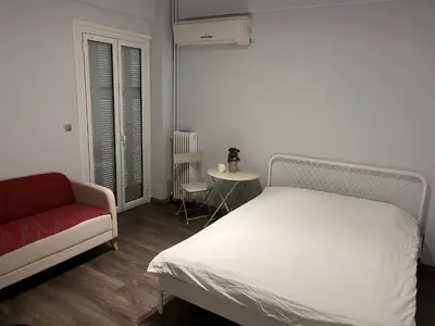 a bedroom with a white bed and a red couch at Studio by Acropolis in Athens
