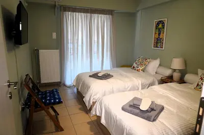 a room with two beds and a television and a window at Urban Maisons Kallithea in Athens