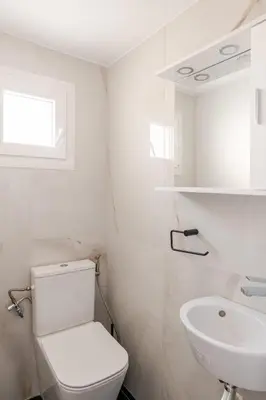 a white bathroom with a toilet and a sink at Cozy, Convenient & Athens in Athens