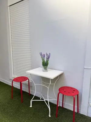a table with two red stools and a table with a vase of flowers at Sophie's apartment near metro in Athens
