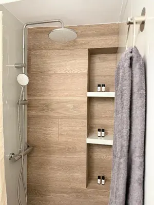 a shower with a wooden door with a towel at Sophie's apartment near metro in Athens