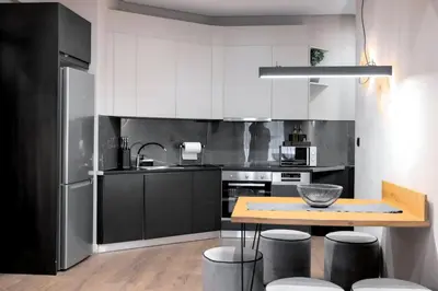 a kitchen with white cabinets and a wooden table at Acropolis Prime Stay in Athens