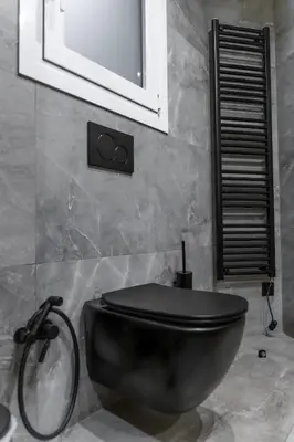 a bathroom with a black toilet and a mirror at Acropolis Prime Stay in Athens