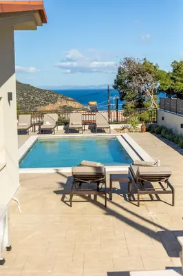 a swimming pool with two benches next to a house at Villa Keyd Mare in Porto Rafti