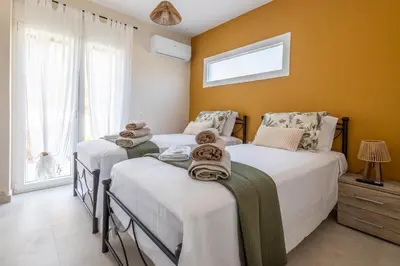 two twin beds in a room with yellow walls at Villa Keyd Mare in Porto Rafti