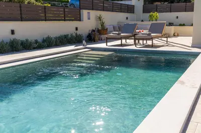 a swimming pool with two chairs next to a house at Villa Keyd Mare in Porto Rafti